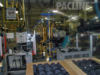Automotive plastic components being moved between processes overhead conveyor that is floor supported.