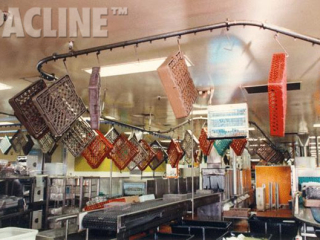 Overhead conveyor transports large plastic totes in this industrial kitchen washing system.
