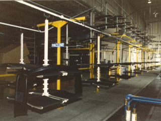 Automotive bumpers being transported from manufacturing to packaging using a PACLINE overhead conveyor.