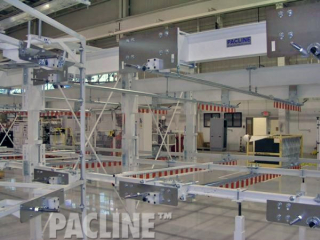 Large gravity rail and trolley transfer overhead conveyor system designed by PACLINE.