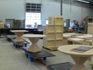 Wood furniture is manually loaded onto slow moving carts on this towline wood finishing conveyor.